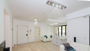 A spacious living area with a white sofa, a dining table, and a chandelier. - ✽ Jerusalem Suites Mamilla ✽ (Jerusalem)