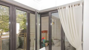 A room with a sliding glass door leading to an outdoor area with a garden and a chair. - ✽ Jerusalem Suites Mamilla ✽ (Jerusalem)