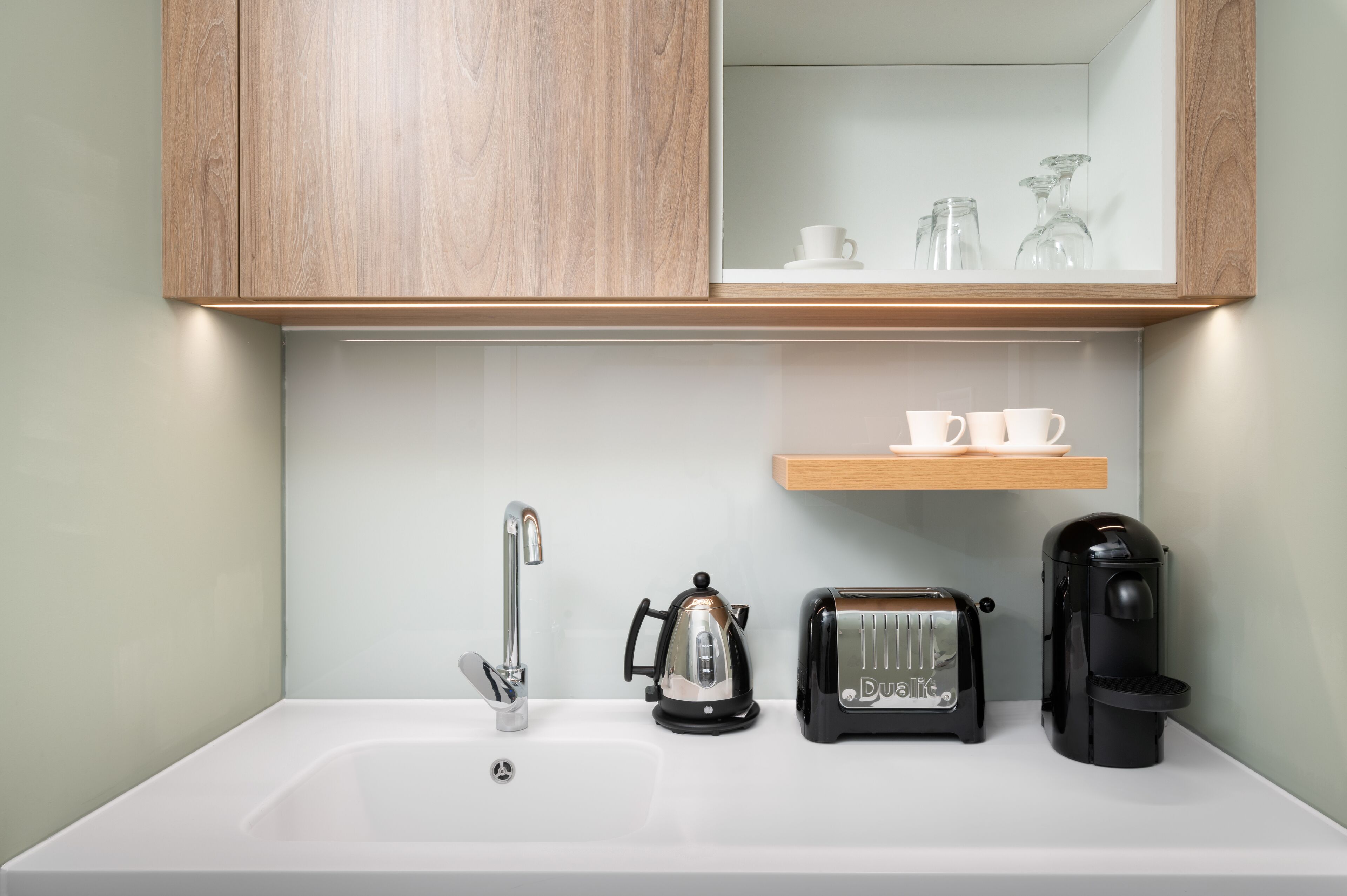 Een keuken met een spoelbak, waterkoker, broodrooster en koffiezetapparaat.