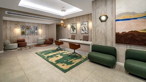 A modern lobby with a skylight, seating area, artwork, and a reception desk. - The Lincoln Suites (London)