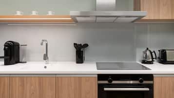 A modern kitchen with a built-in oven, a coffee maker, a toaster, and a kettle on the countertop.
