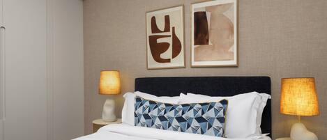 Een hotelkamer met een bed, twee bedlampen, een hoofdbord en twee abstracte schilderijen aan de muur.