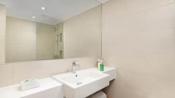 Un baño moderno con dos lavamanos, un espejo grande y una ducha.