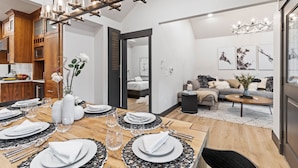 A modern dining area with a wooden table set for six, a chandelier, and a view into a bedroom. - 909 Park Ave 5 Bedroom Home by RedAwning (Park City)