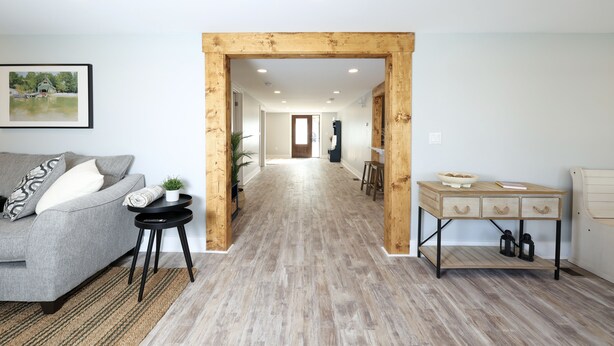 Una sala moderna con un sofá gris, una mesita auxiliar negra y un escritorio de madera con cajones.