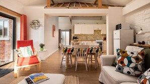 A modern interior with a dining area, kitchen, and seating space. - 2 bedroom family friendly barn conversion, luxury indoor heated pool onsite (Fakenham)
