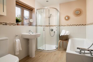 A modern bathroom with a glass-enclosed shower, a sink, a toilet, and a bathtub.