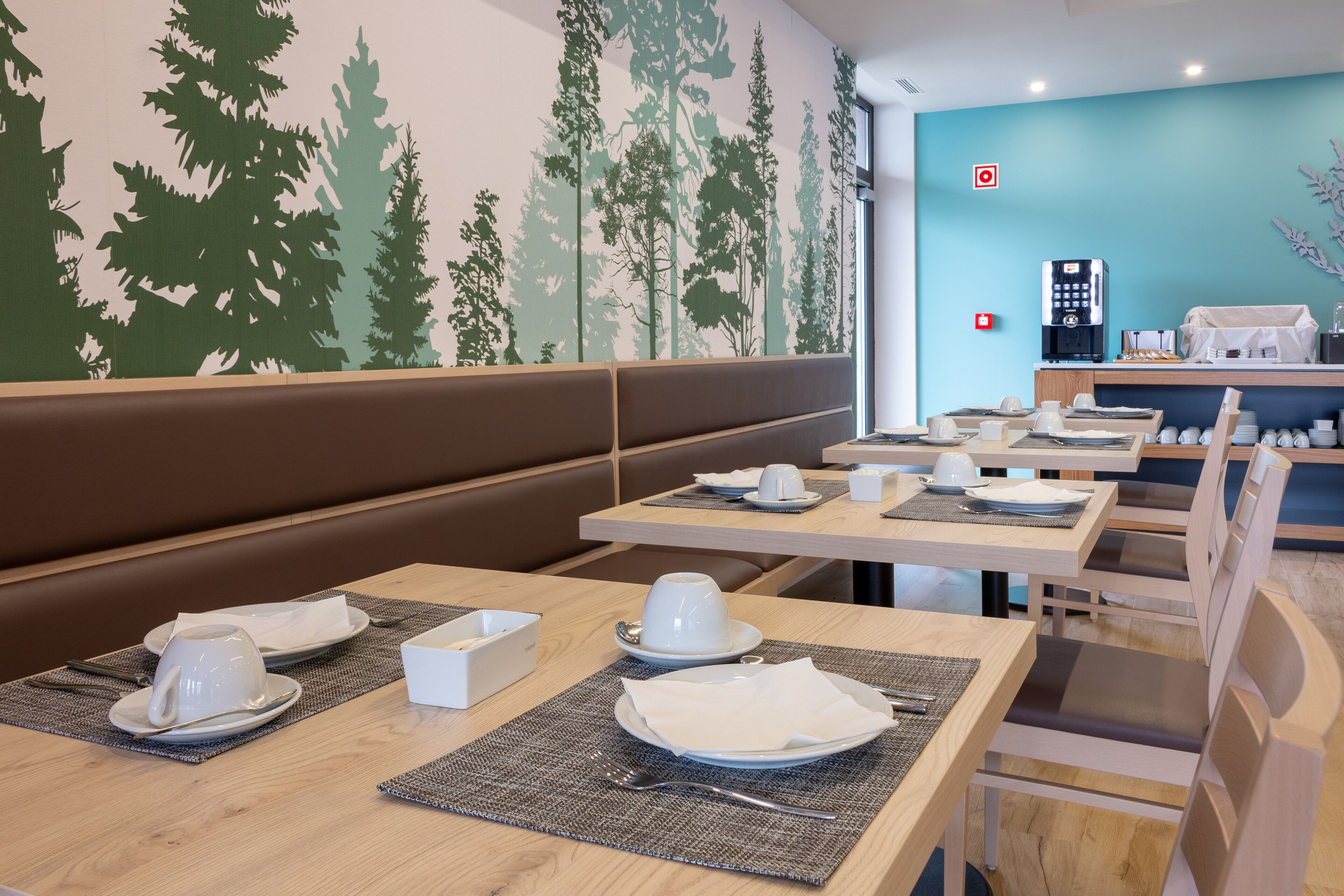 Un restaurant avec des banquettes et des tables, chacune étant dressée avec des assiettes, des tasses et des couverts.