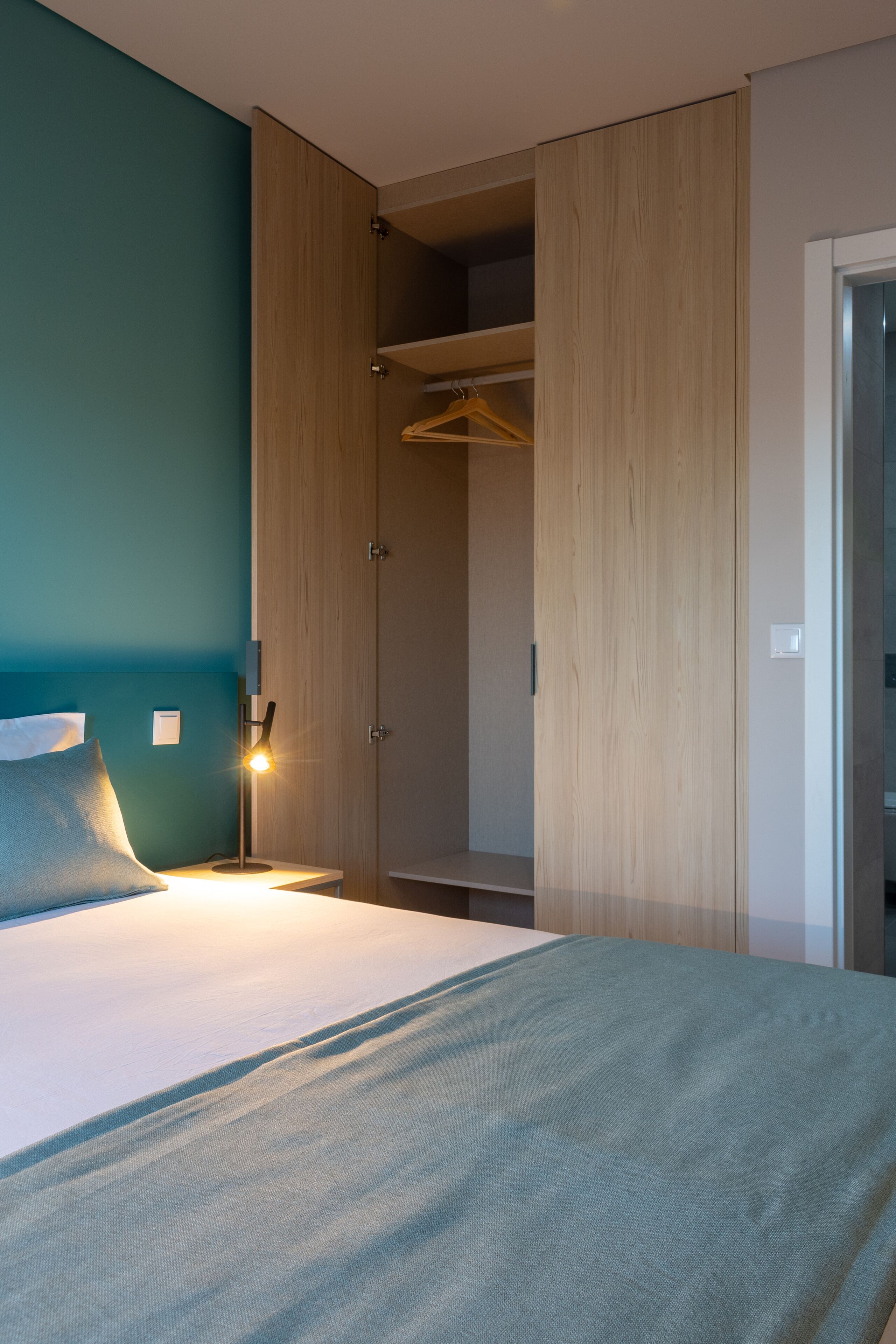 Une chambre à coucher comprenant un lit, une lampe de chevet, une armoire et un placard.