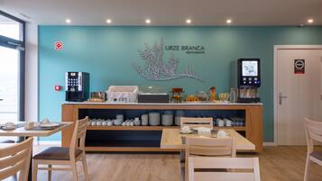 Un restaurante con una pared azul verdoso, una máquina de café y un expositor de menú.