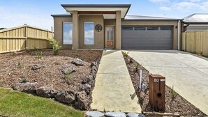A modern two-story house with a garage, a front yard with a pathway, and a mailbox marked with the number 80. - Relax at Torquay Dunes: Shops and Beaches Nearby (Torquay)