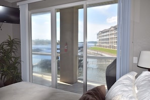 A hotel room with a large sliding glass door leading to a balcony with a view of a water body and a building across the water. - Welcome to Paradise!Screened Patio-LANDS END 12 x 36 Boat slip  Sleeps 6-8
GRILL (Osage Beach)