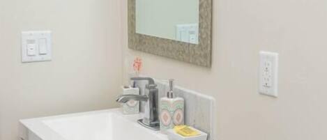 A bathroom with a white sink, a mirror, a toilet, and a cabinet with drawers.