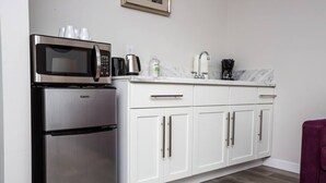 A compact kitchen with a Galanz refrigerator, a microwave, a coffee maker, and a sink with a faucet.