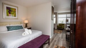 A hotel room with a large bed, a bench, a desk, and a chair.