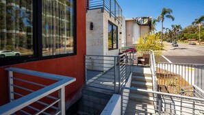 Ein Gebäude mit roter Fassade, großen Fenstern und einer sichtbaren Treppe, die zu einer zweiten Etage führt.