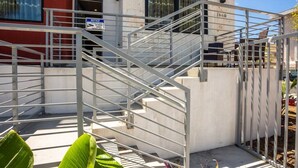 Eine Metalltreppe führt zu einem Gebäudeeingang, eine Schilderung kennzeichnet den 24-Stunden-Service.