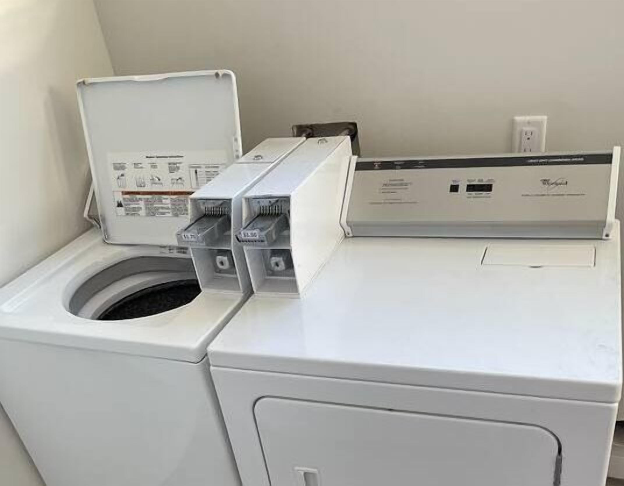 A front-loading washer and dryer in a laundry room with a wooden floor.