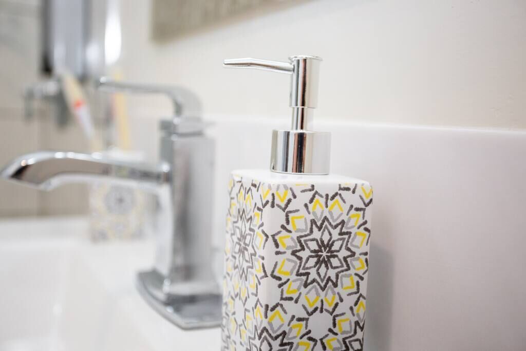 A bathroom with a modern faucet and a patterned soap dispenser.