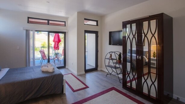 Hotelkamer met een bed, een televisie, een schuifdeur naar een balkon en een klein zithoekje met een stoel en tafel.