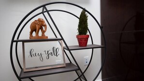 Een rond metalen schap met een bordje met de tekst 'hey yall', een houten olifantbeeldje en een bloempot.