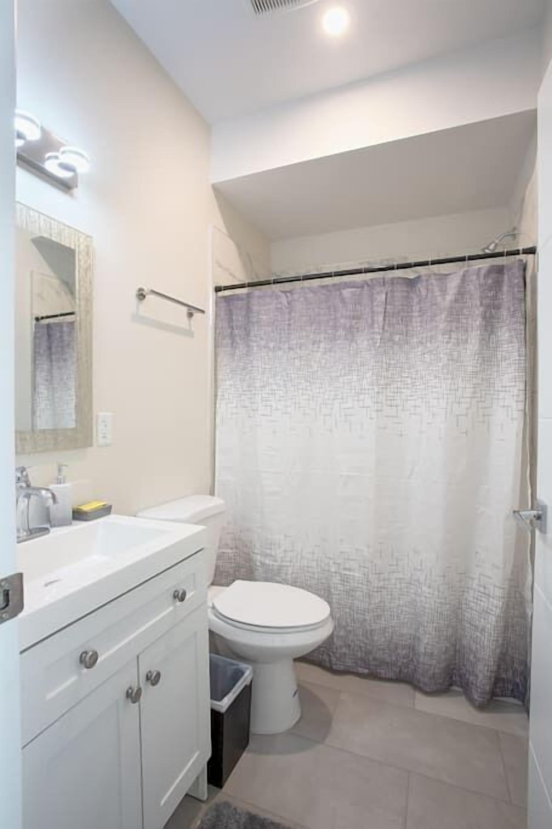 Un bagno con un lavandino bianco, un water e una tenda da doccia.