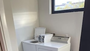 A compact laundry room with a washing machine and dryer, a small sink, and a window above the dryer.
