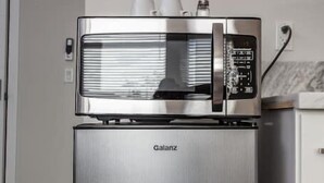 A stainless steel Galanz refrigerator with a control panel and two white cups on top.