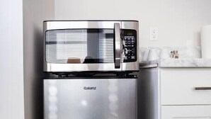 Een Galanz koelkast van roestvrij staal in een keuken met witte kastjes en een houten vloer.