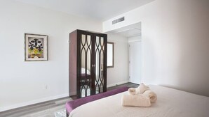 Een moderne hotelkamer met een groot bed, een paarse accentmuur en een decoratieve keermuur.
