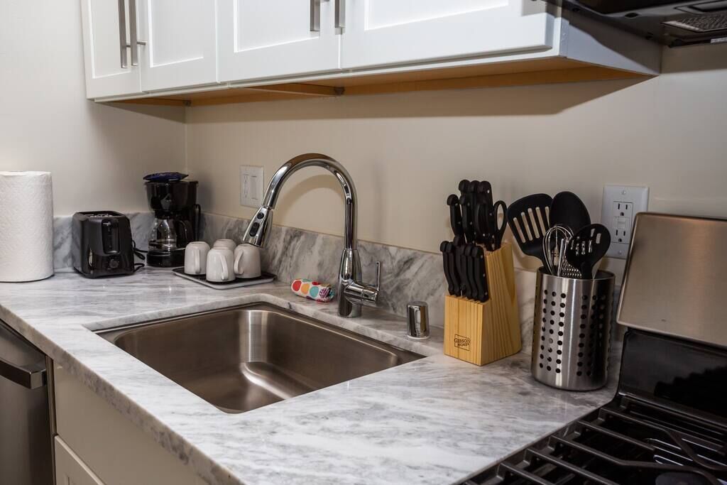 A kitchen with a stainless steel sink, a coffee maker, a toaster, and a knife block.