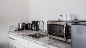Eine moderne Küche mit Mikrowelle, Kaffeemaschine und Wasserkocher aus Edelstahl.