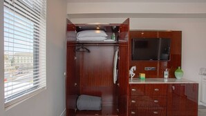 Une chambre dotée d’une armoire intégrée, d’une télévision et d’un petit coin cuisine.
