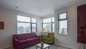 Un salon avec un canapé violet, un fauteuil vert et une table basse.
