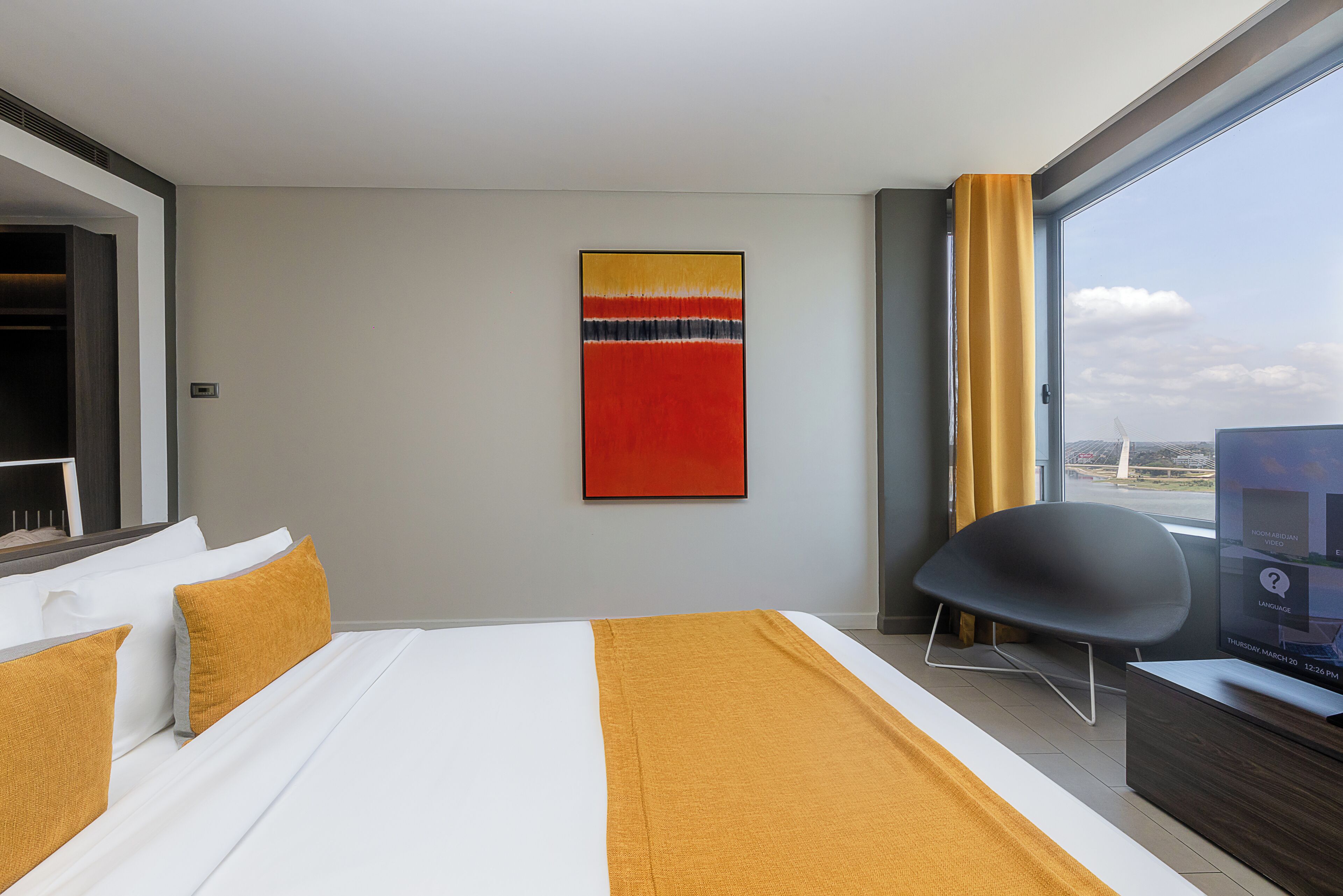 Une chambre d’hôtel avec un lit, une chaise, une télévision et une fenêtre donnant sur un paysage agréable.