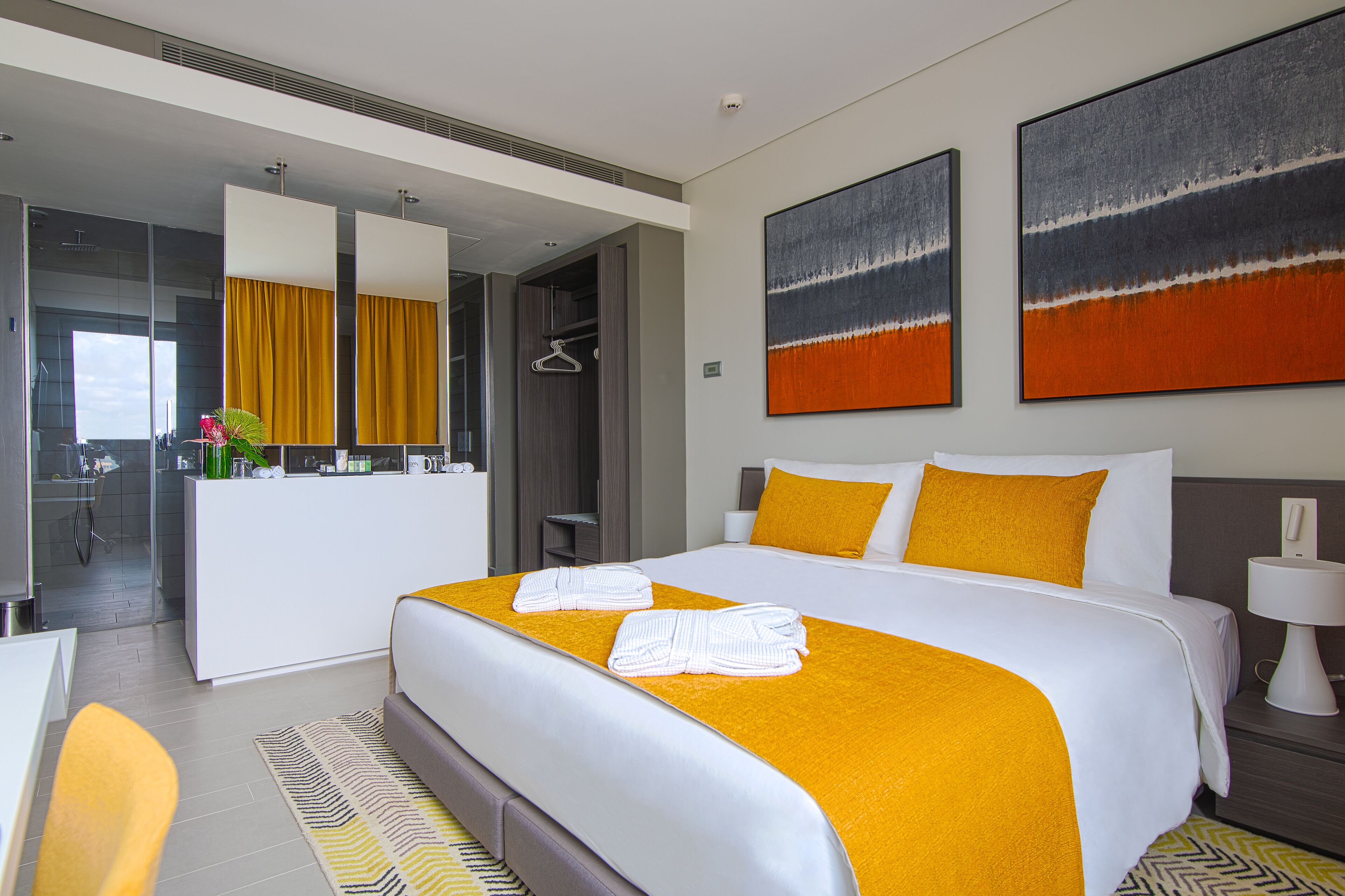 Ein modernes Hotelzimmer mit einem großen Bett, einem Schreibtisch und einem durch eine geöffnete Tür einsehbaren Badezimmer.