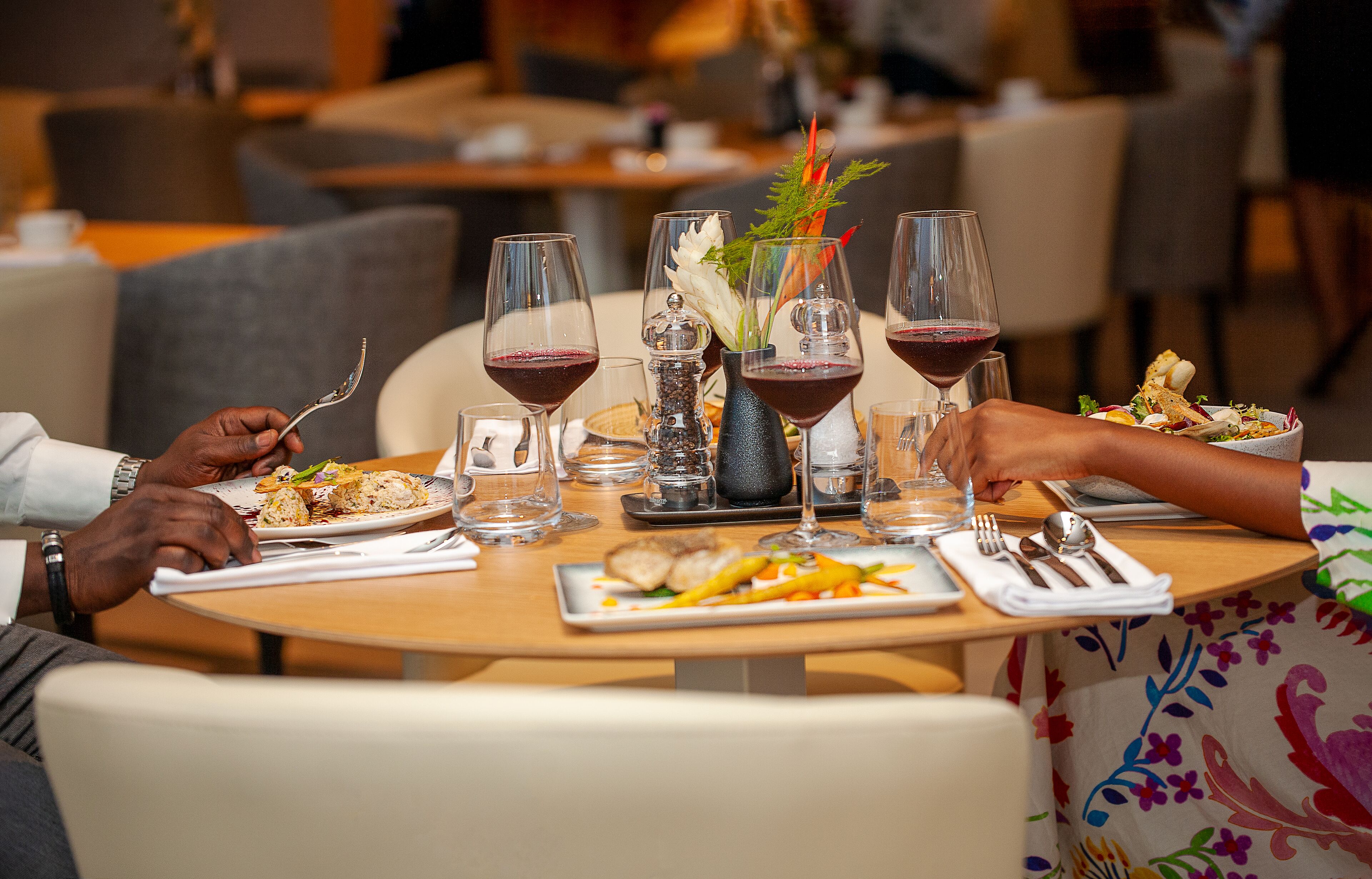 A dining table set with plates of food, wine glasses, and cutlery.