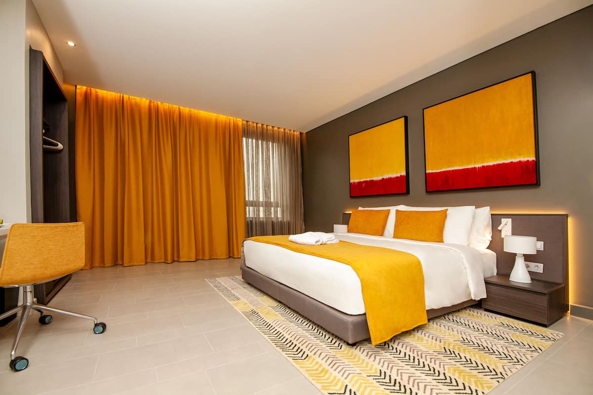 A modern hotel room with a large bed, a desk, and a chair.