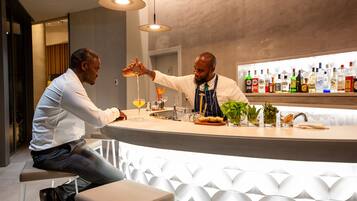 A bar area with a counter, seating, and a variety of bottles on the shelf.