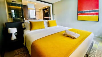 A hotel room with a large bed, a nightstand, a mirror, and a red abstract painting on the wall.