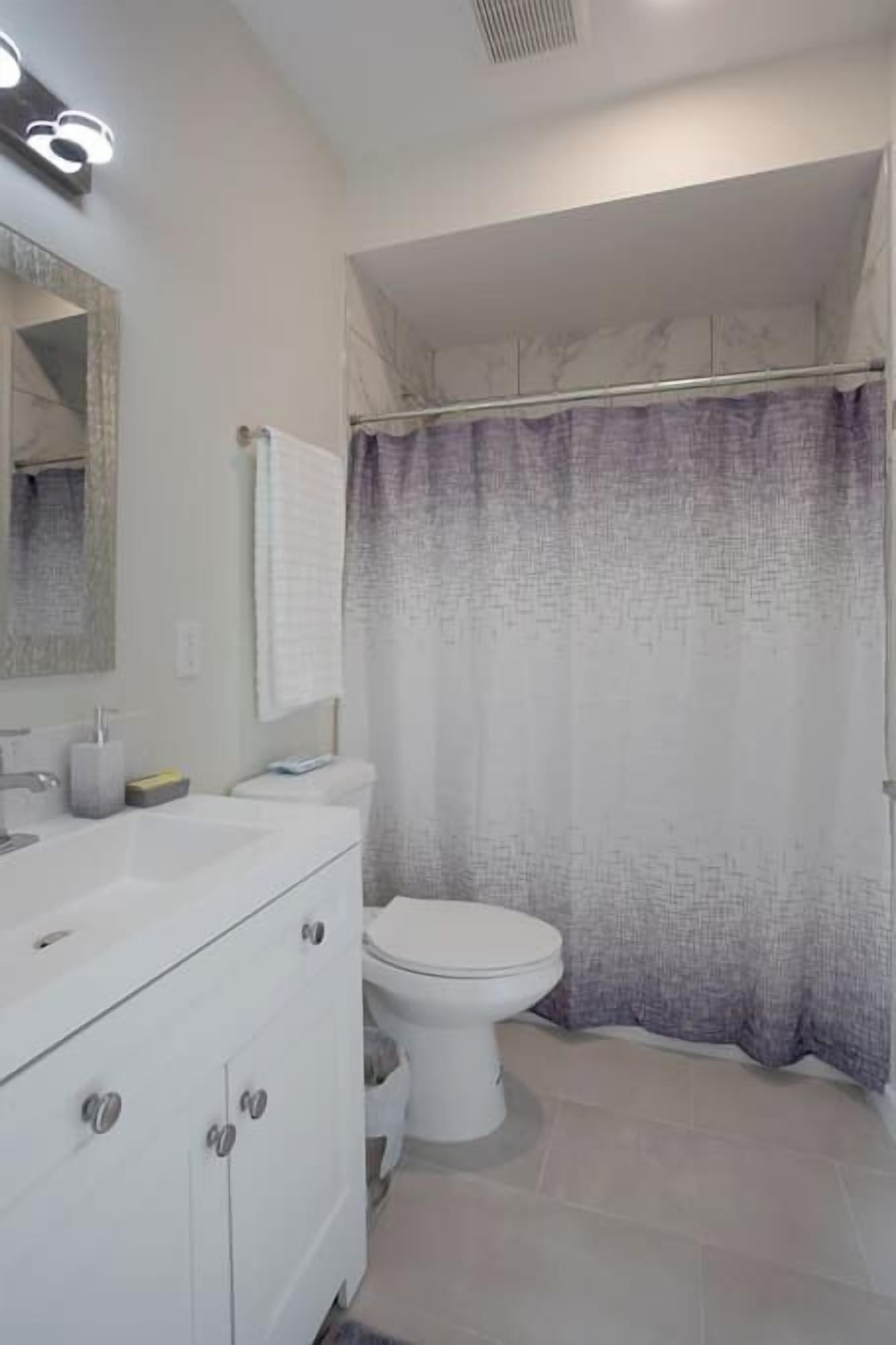 A bathroom with a white sink, mirror, and toilet.