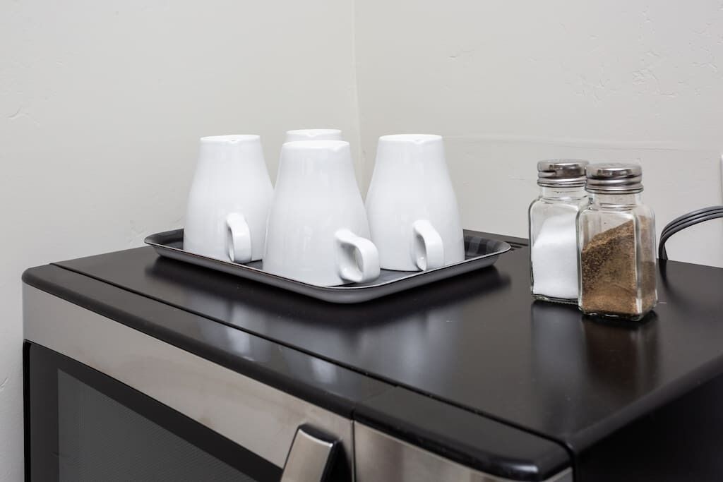 A kitchen counter with a tray holding white cups and two salt and pepper shakers.