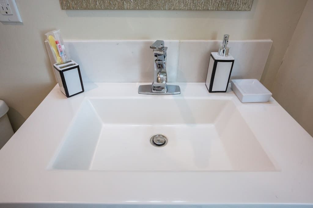 A white bathroom sink with a chrome faucet, two toothbrush holders, and a soap dish.