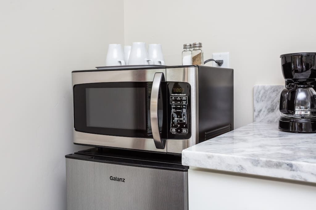 A compact kitchen with a stainless steel microwave and a built-in refrigerator.