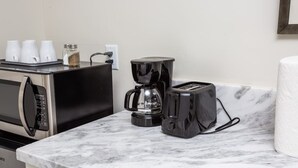 Eine Küche mit Mikrowelle, Kaffeemaschine, Toaster und einer Marmorarbeitsplatte.