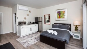 Een moderne slaapkamer met een bed, nachtkastje en een kleine keukenhoek.