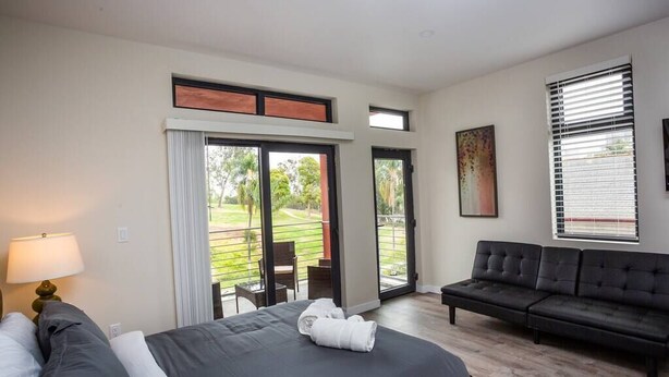 Een slaapkamer met een bed, een bank, een balkon met een stoel en een schilderij aan de muur.