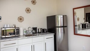Een moderne keuken met witte kasten, een roestvrijstalen koelkast, een magnetron en een koffiezetapparaat.