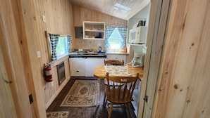 Une cuisine de taille réduite avec des murs en bois, une cuisinière, un évier et une table à manger avec des chaises.
