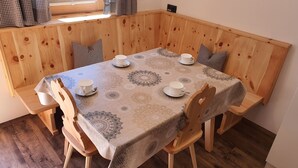 Een houten eettafel met een tafelkleed met dessin, omringd door houten stoelen, gedekt voor vier personen.